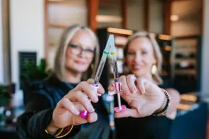 Two women at a med spa in Athens holding syringes for aesthetic injectable treatments, smiling in a professional setting.